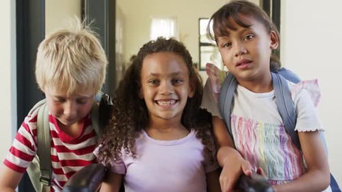 Diverse school-age children posing for camera in entry, leaning toward wheelchair with backpacks