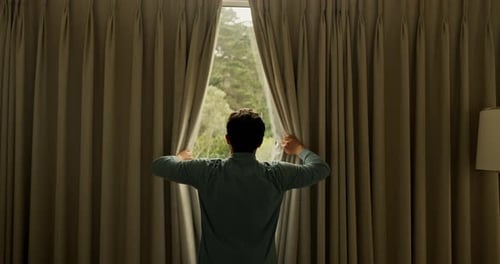 Man Opens Curtains to Green Landscape View