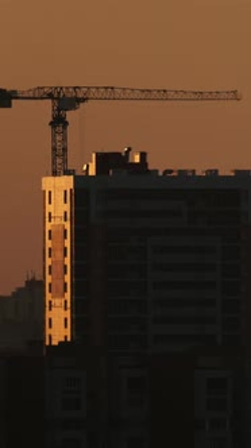 Construction Cranes Near Residential Apartments View on Sunrise