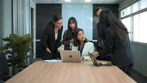 Group of business people looking at computer and discussing in modern office