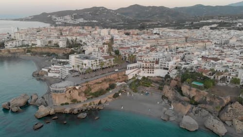 Drone aerial view rotating around Europe's Balcony with the white city of Nerja at the background
