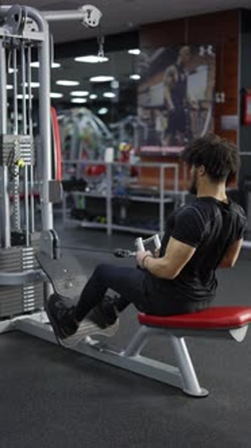 Determined Man Doing Cable Row Exercise at Gym
