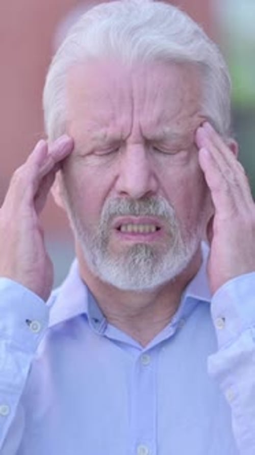 Senior Man Rubbing Temples Suffering from Headache