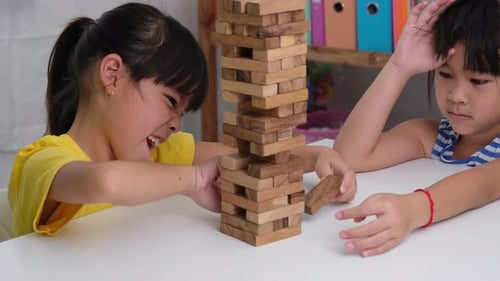 Cute Asian siblings having fun playing Jenga together.