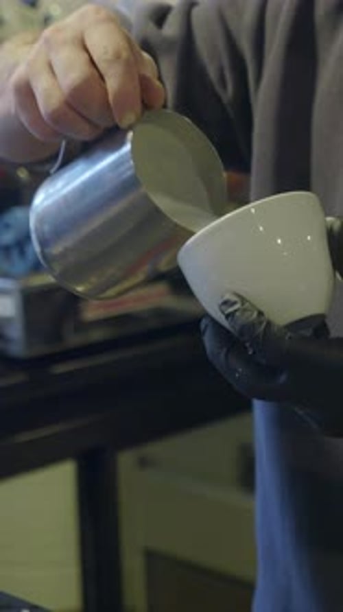 Barista Pouring Steamed Milk into Coffee Cup