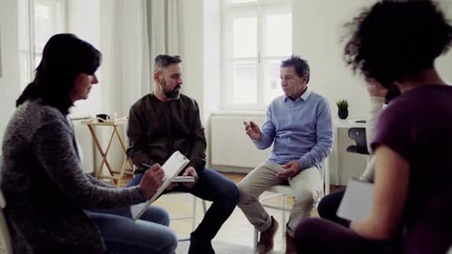 Men And Women Sitting In A Circle During Group Therapy, Talking.