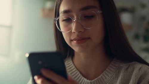 Close up of caucasian teenage girl browsing phone in her bedroom. Shot with RED helium camera in 8K.