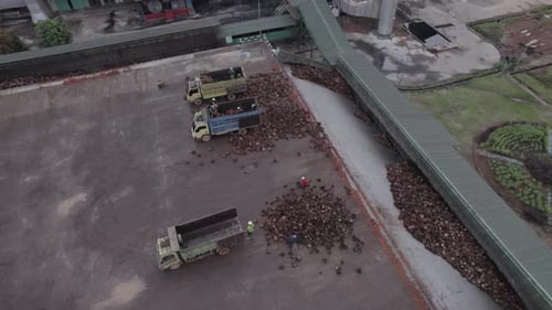 Aerial View of Workers Unloading Trucks at Factory