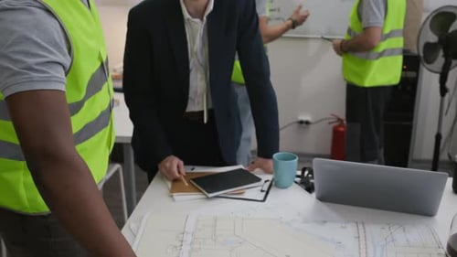 Diverse Foreman and Engineer Planning Work with Blueprints in Office