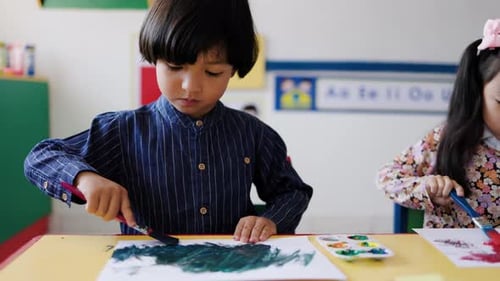 Asian kid painting during art class in kindergarten class room. Multiracial children students