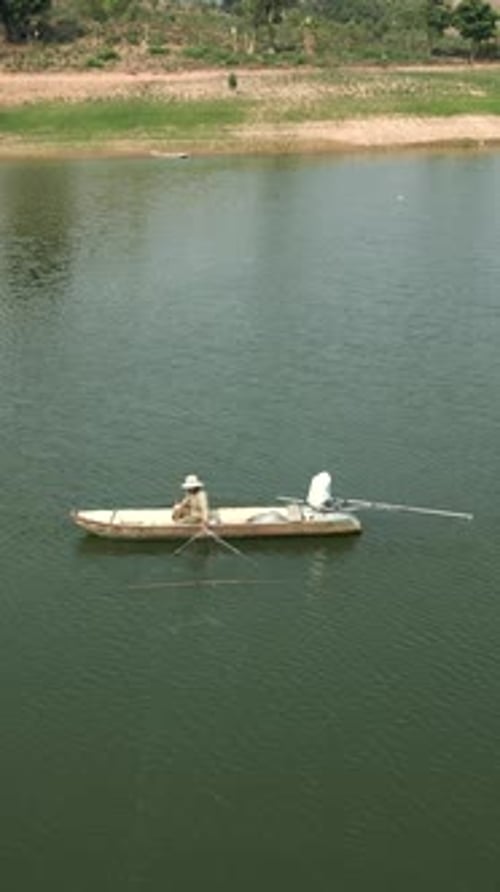 Drone Flying Over the Great River Where a Fisherman Works From His Small Boat in Vietnam