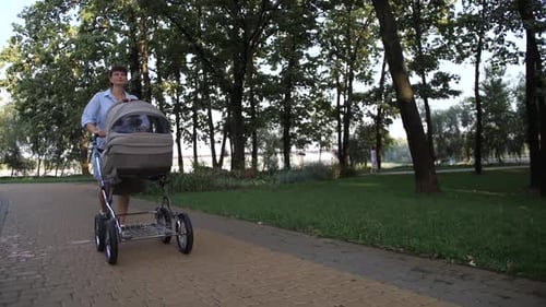 Beautiful Mother Walking in the Park with a Stroller