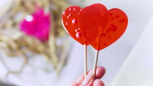 Heart Lollipops Held in Hand Against Soft Background