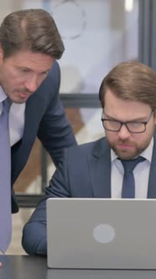 Two Men in Suits Looking at Laptop in Office