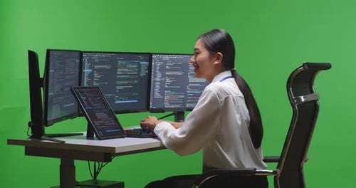 Woman Developer Working With Tablet While Write Code With Multiple Screens In Green Screen Studio