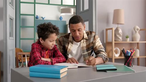 African American Father Helping School Age Son to Do Homework at Home