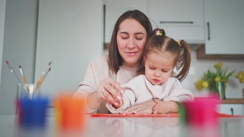 Mother and Child Painting Together in Kitchen