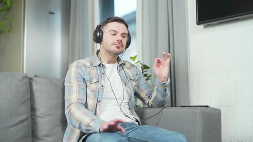 Man Listens to Music on Headphones Indoors