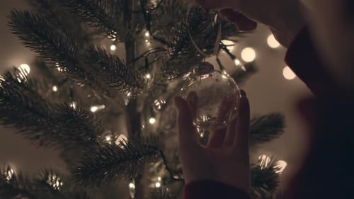 Decorating Lit Christmas Tree with Glass Ornament