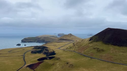 Helgafell volcano and Icelandic coastline under cloudy skies, remote and rugged, aerial view