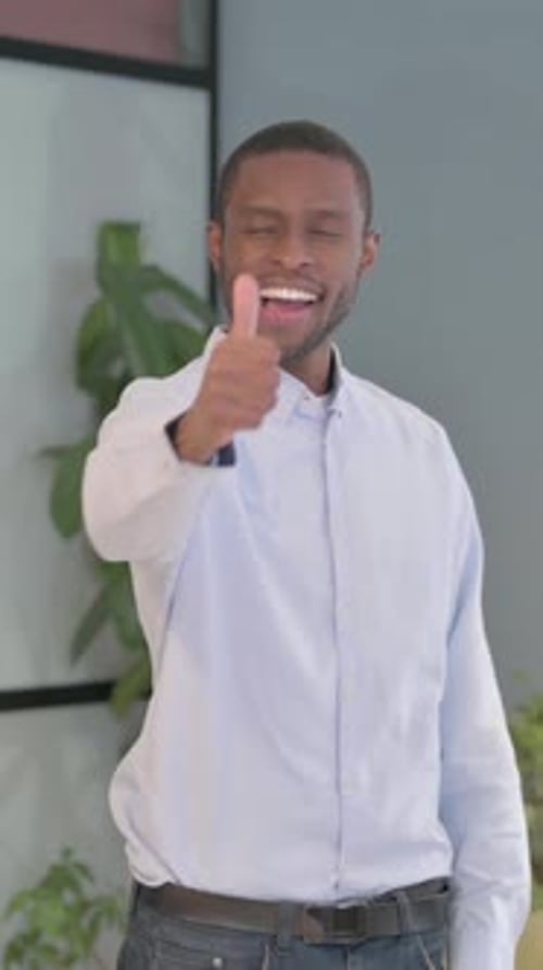 Smiling Man Giving Thumbs Up in Indoor Setting