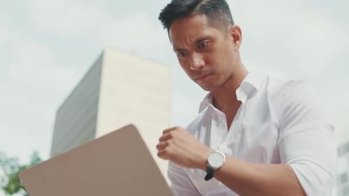 Close up of young businessman freelancer working on laptop outside