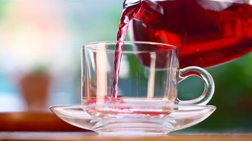 Pouring Red Tea into Clear Glass Teacup