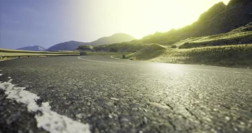 Scenic Mountain Road Winding Through Lush Green Hills Under Golden Light