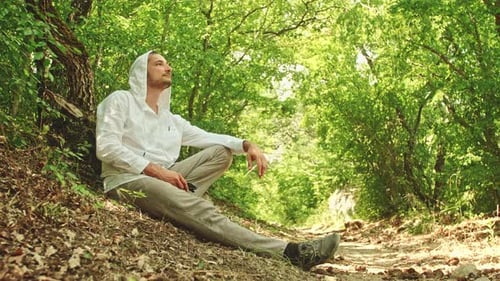 A Hiker Rests on the Side of a Trail in the Forest on a Hot Summer Day