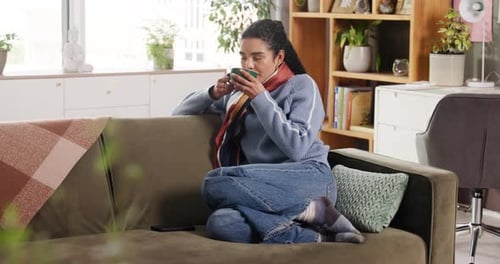 Woman Relaxing on Sofa with a Warm Drink