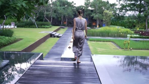 Elegant young woman strolling through a lush green garden on a sunny day