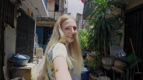 Smiling woman walks down narrow urban Bangkok street