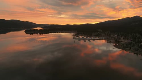 Vibrant sunset over lake with glowing clouds reflecting across calm mountain waters