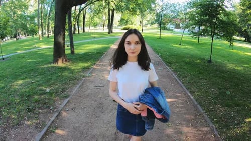A Beautiful Young Girl Strolls Along a Walkway in a Summer Park