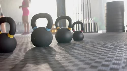 Kettlebells lined up on gym floor, ready for female fitness workout session, copy space