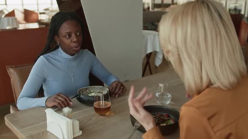 Multiethnic Girlfriends Chatting while Enjoying Lunch in Restaurant