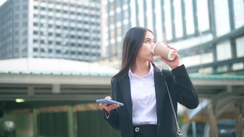 Businesswoman Using Phone and Drinking Coffee in City