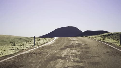 Driving on Desert Road with Mountains Under Clear Sky