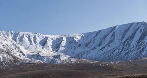 Zeitraffer der Sonnenbewegung am kristallklaren Himmel über dem Schneeberggipfel, gelbem Gras auf der Herbstwiese