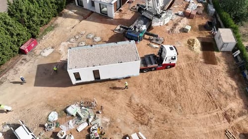 Vorgefertigtes modulares Haus, das mit einem LKW zur Baustelle transportiert wird. Kreisen aus der Luft von oben nach unten