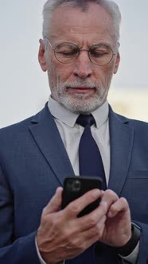 Serious Businessman Types Message to Partner on Smartphone