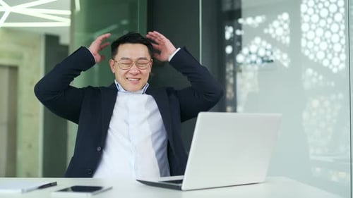 Smiling Man Works on Laptop in Corporate Office