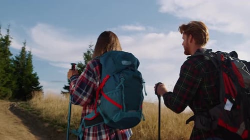 Couple Hike Through Rural Nature with Backpacks and Poles