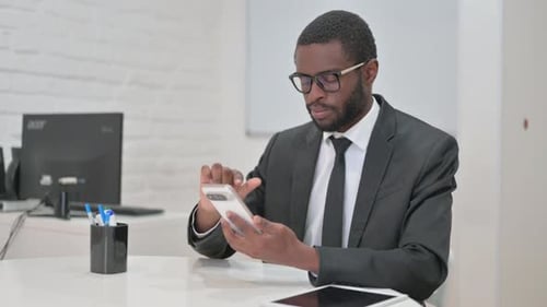 Adult Man Works in Bright Office on Smart Phone