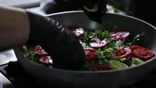Hands arranging vegetables in large pan