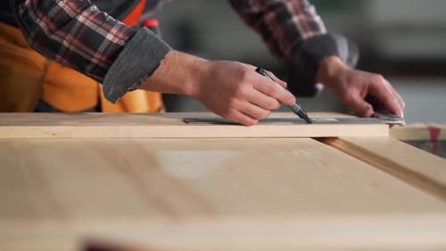 Close-up of male hands of a carpenter drawing a line at an angle