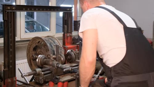A Car Mechanic Repairs a Bent Rim of a Car Damaged Steel Auto Mechanic Services