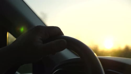 Hand Driving Car into Beautiful Golden Sunrise