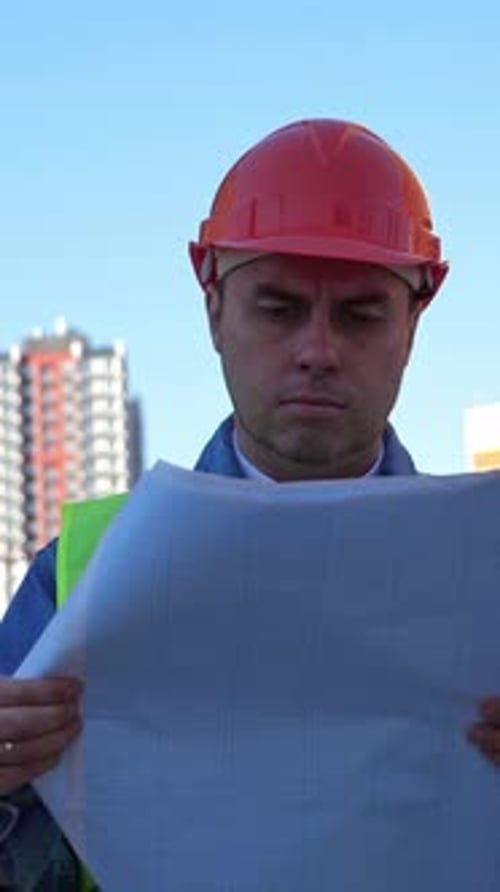 Engineer with Blueprint in Protective Helmet at Construction Site Outdoors Vertical