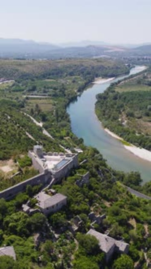 Vue aérienne de Počitelj, en Bosnie-Herzégovine, montrant une rivière, un paysage verdoyant et des ruines historiques